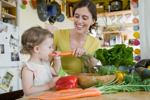 Woman and toddler in kitchen with vegetables