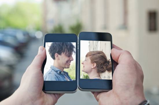 Young couple communicating via two smartphones