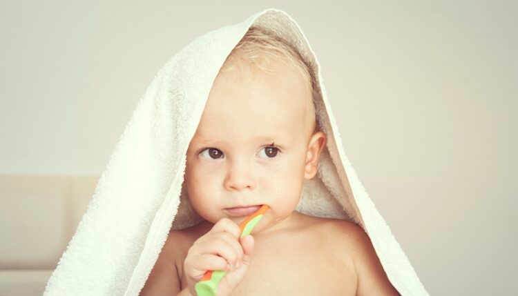 Baby brushing his teeth with a toothbrush after a shower